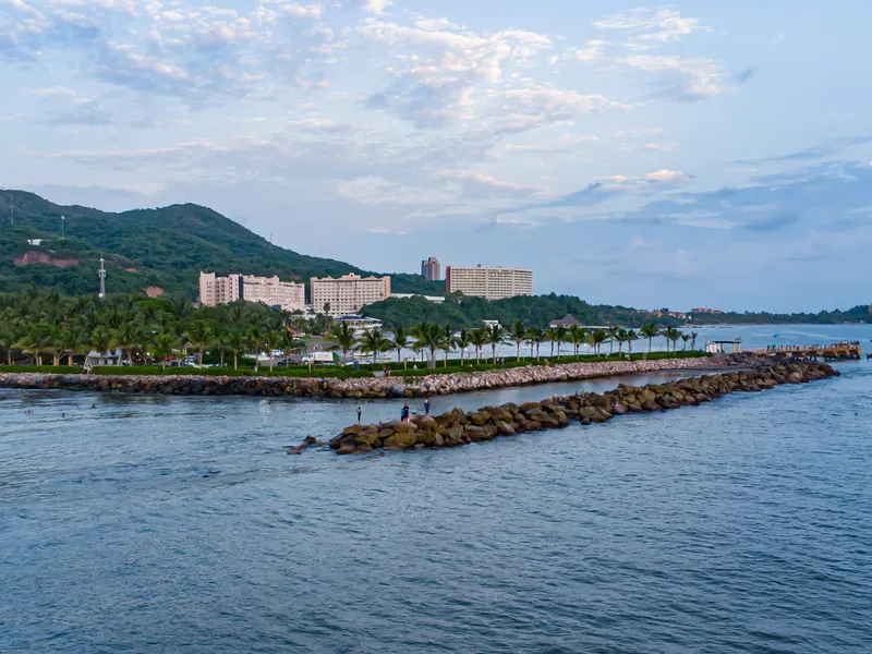 Muelle y escollera de la bah&iacute;a de Zihuatanejo con la costa de Ixtapa al fondo