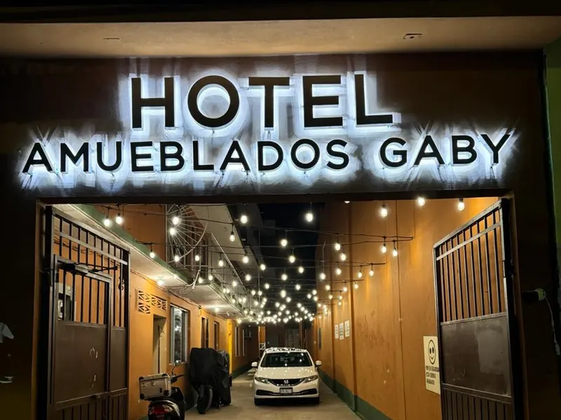 Entrada iluminada del Hotel Amueblados Gaby con su letrero y pasillo