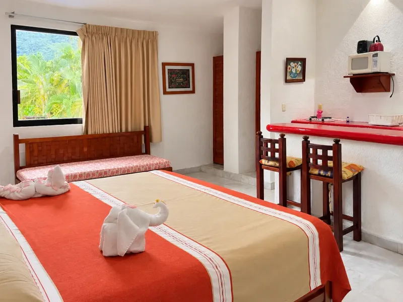 Habitaci&oacute;n de Hotel Villas Mercedes con cama, cocineta y ventana al jard&iacute;n