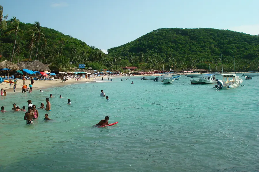Agua turquesa y bañistas en Playa Las Gatas, Zihuatanejo, protegida por un arrecife